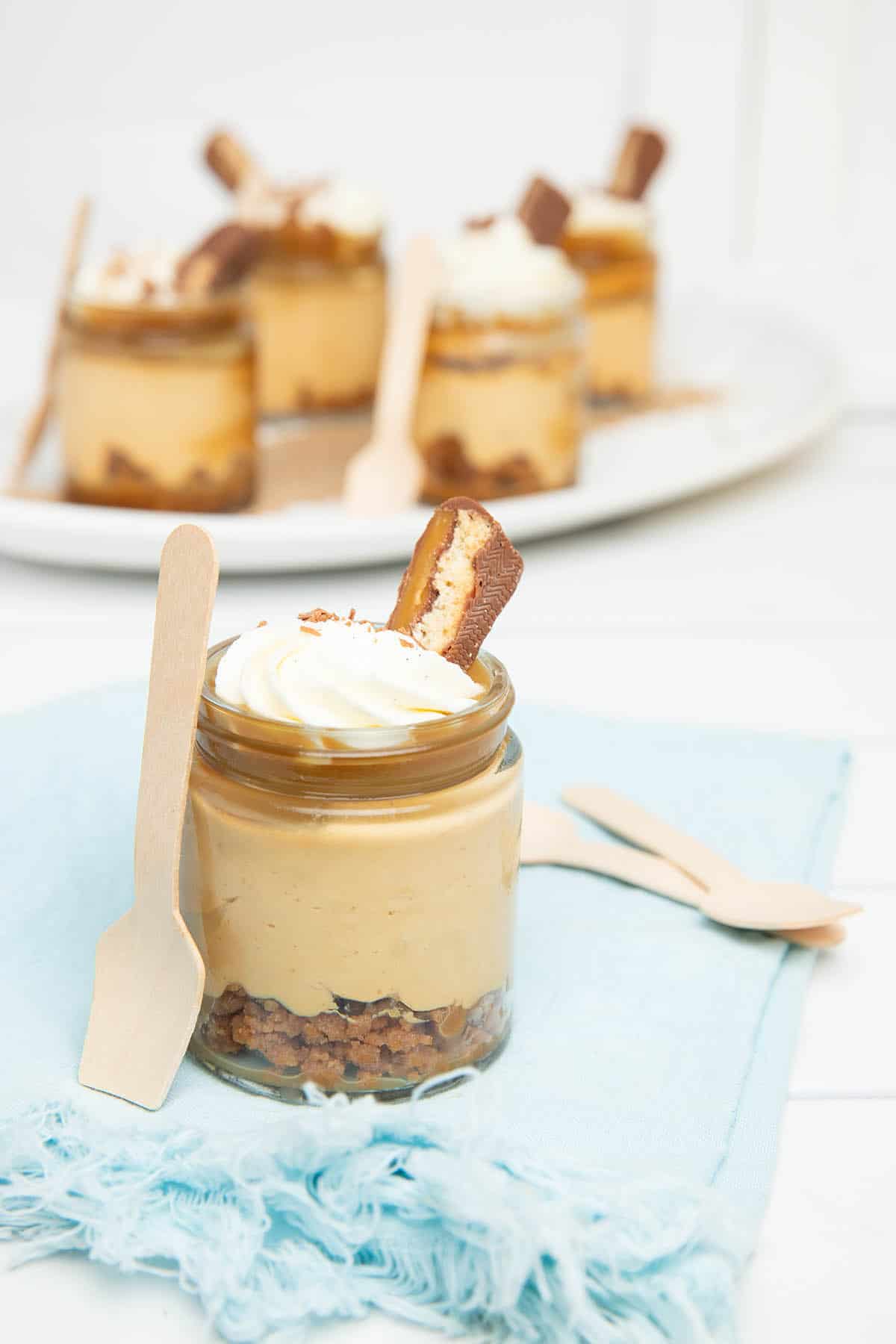 Little pots of cheesecake on a blue napkin.