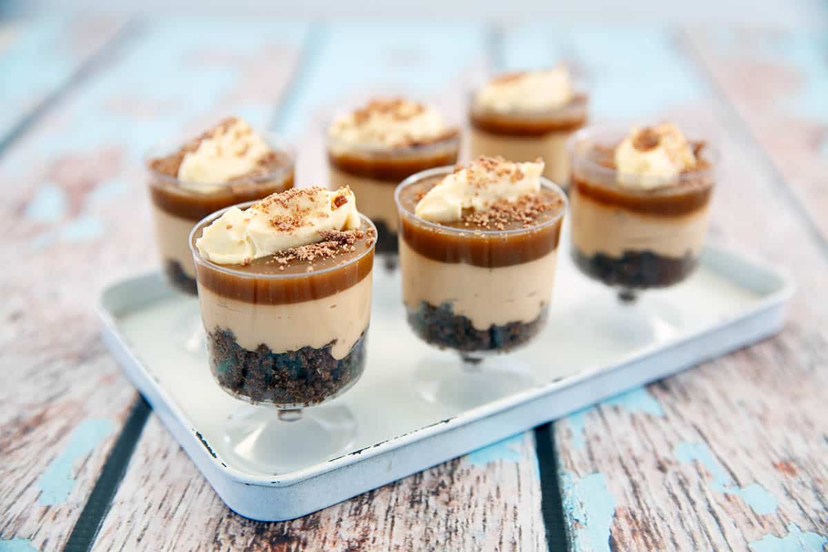 six salted caramel cheesecakes on a white platter, blue background