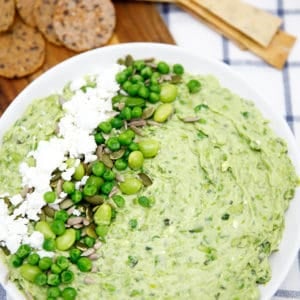Smashed Pea and Bean Dip on a white plate with teatowel