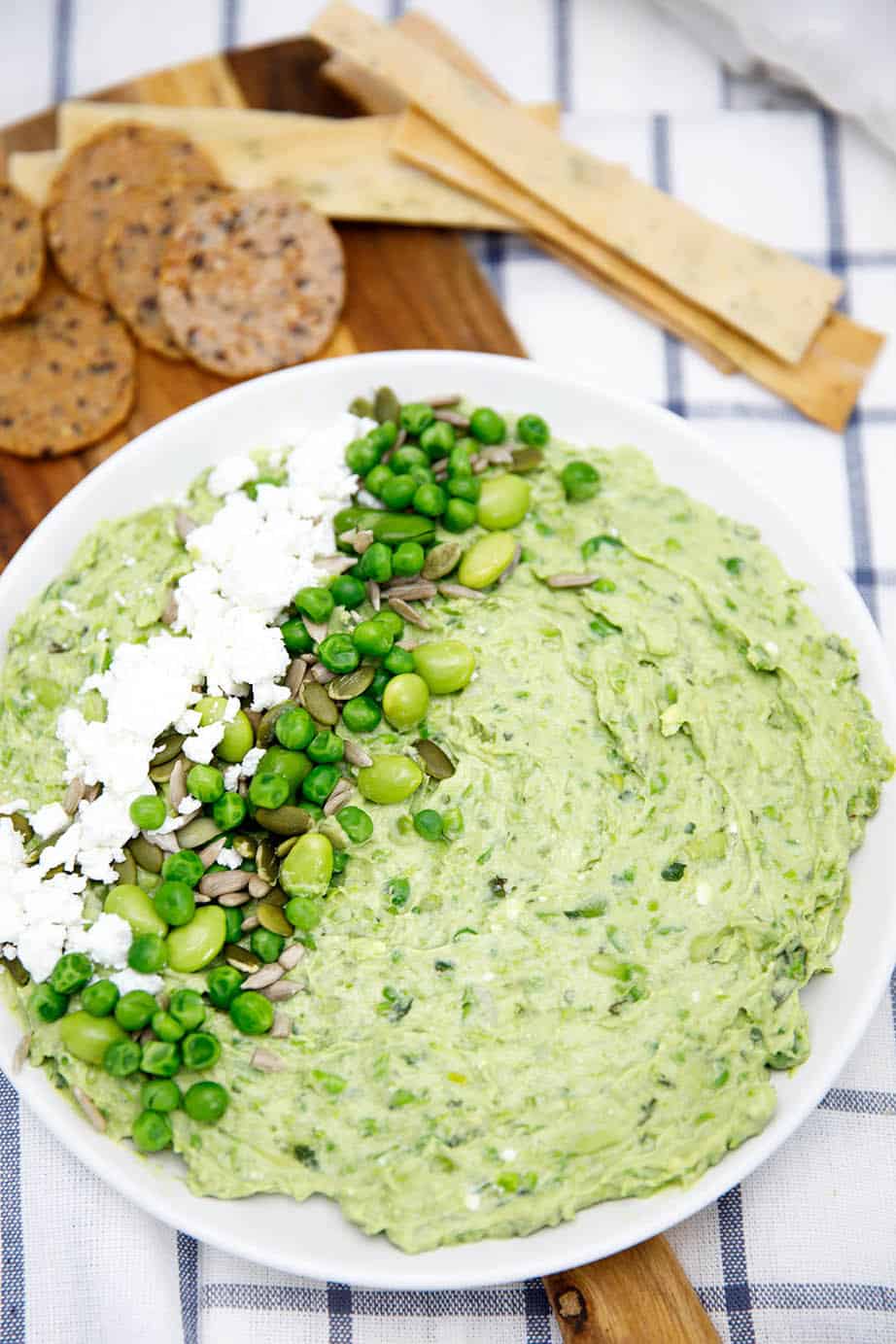 Smashed Pea and Bean Dip on a white plate with teatowel