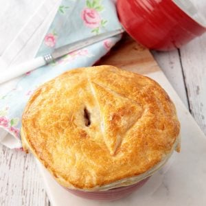 Homemade Guinness pie in a red pot on a wooden background