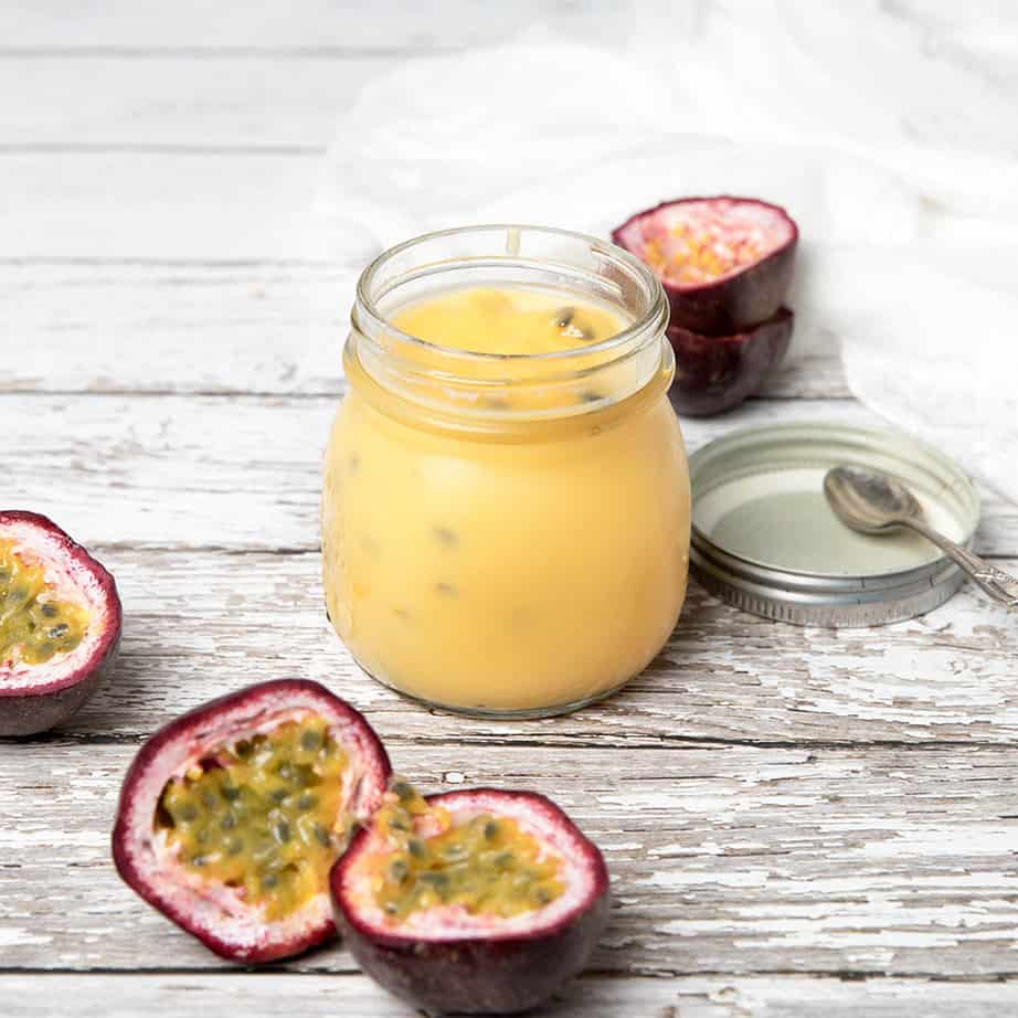 Passionfruit curd in a glass jar on a wooden background