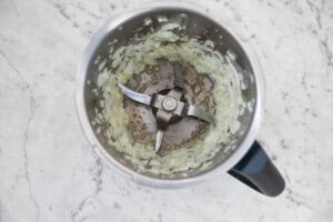 Chopped onion and garlic in the Thermomix bowl on marble background.