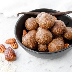 Thermomix Salted Pecan Bliss Balls on a white background, pecans and vanilla bean in photo