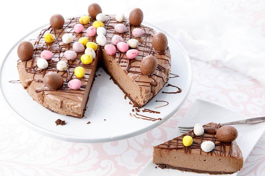 Whole chocolate cheesecake with a slice on a plate decorated in Easter Eggs