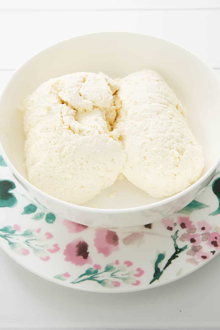 Portrait image of homemade ricotta cheese on floral crockery