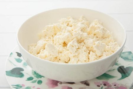 Close up of fresh homemade ricotta in a white bowl on flora background