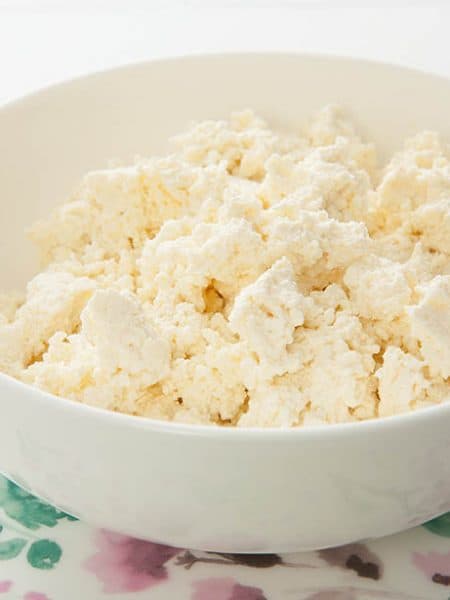 Close up of fresh homemade ricotta in a white bowl on flora background