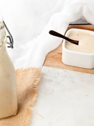 A bottle of homemade Caesar Salad Dressing on a white background