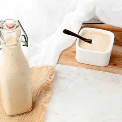 A bottle of homemade Caesar Salad Dressing on a white background