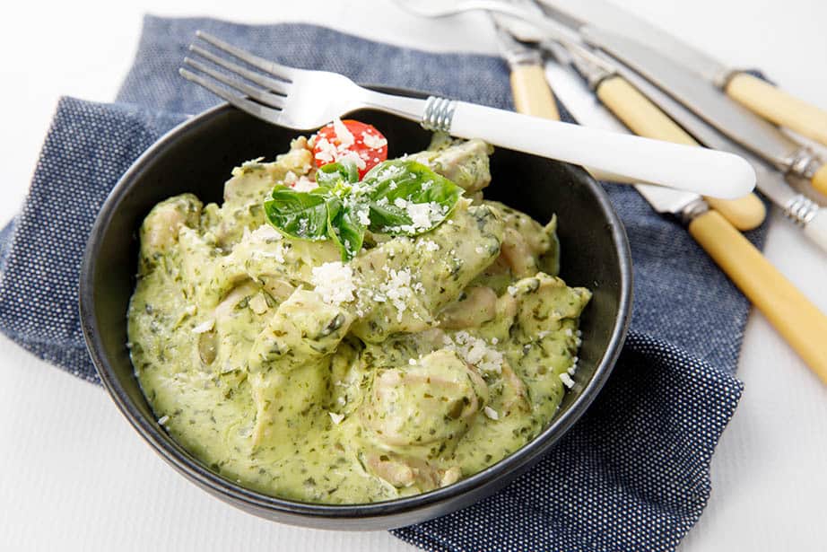 Landscape shot of creamy pesto chicken in a bowl on denim teatowel