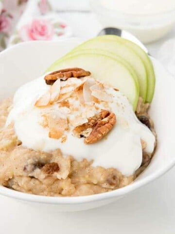 A bowl of Apple Pie Oatmeal topped with yoghurt, nuts, coconut and apple