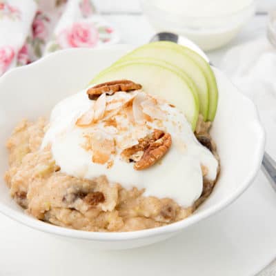 A bowl of Apple Pie Oatmeal topped with yoghurt, nuts, coconut and apple