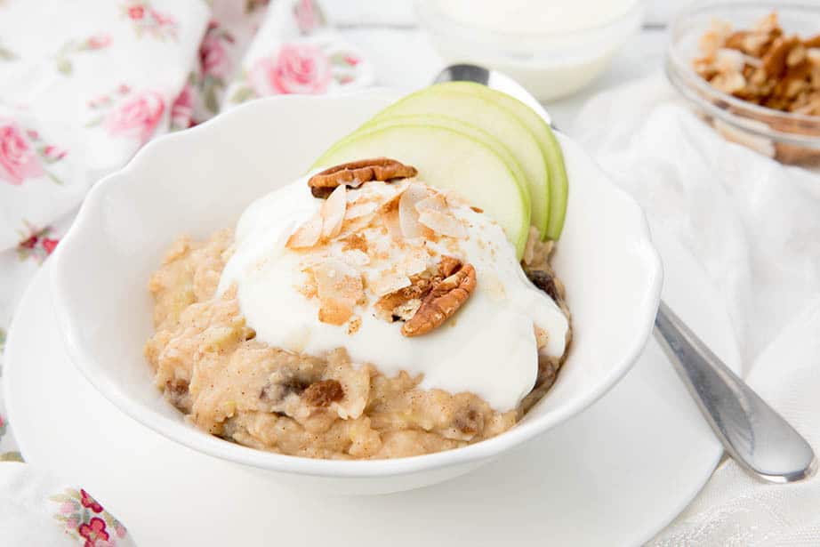 A bowl of Apple Pie Oatmeal topped with yoghurt, nuts, coconut and apple