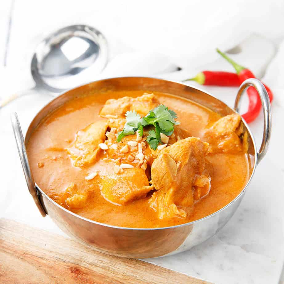 Square crop chicken curry in metal bowl on a white background