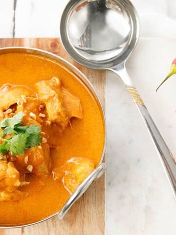 Overhead shot of Ghanaian Peanut Curry in a metal bowl on a white background