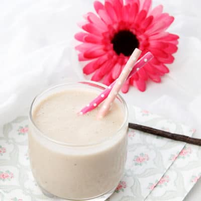 Square image smoothie on napkin with a pink gerbra flower and vanilla bean