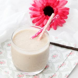 Portrait image of healthy smoothie with a pink flower on a napkin and white background