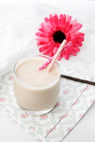 Portrait image of healthy smoothie with a pink flower on a napkin and white background