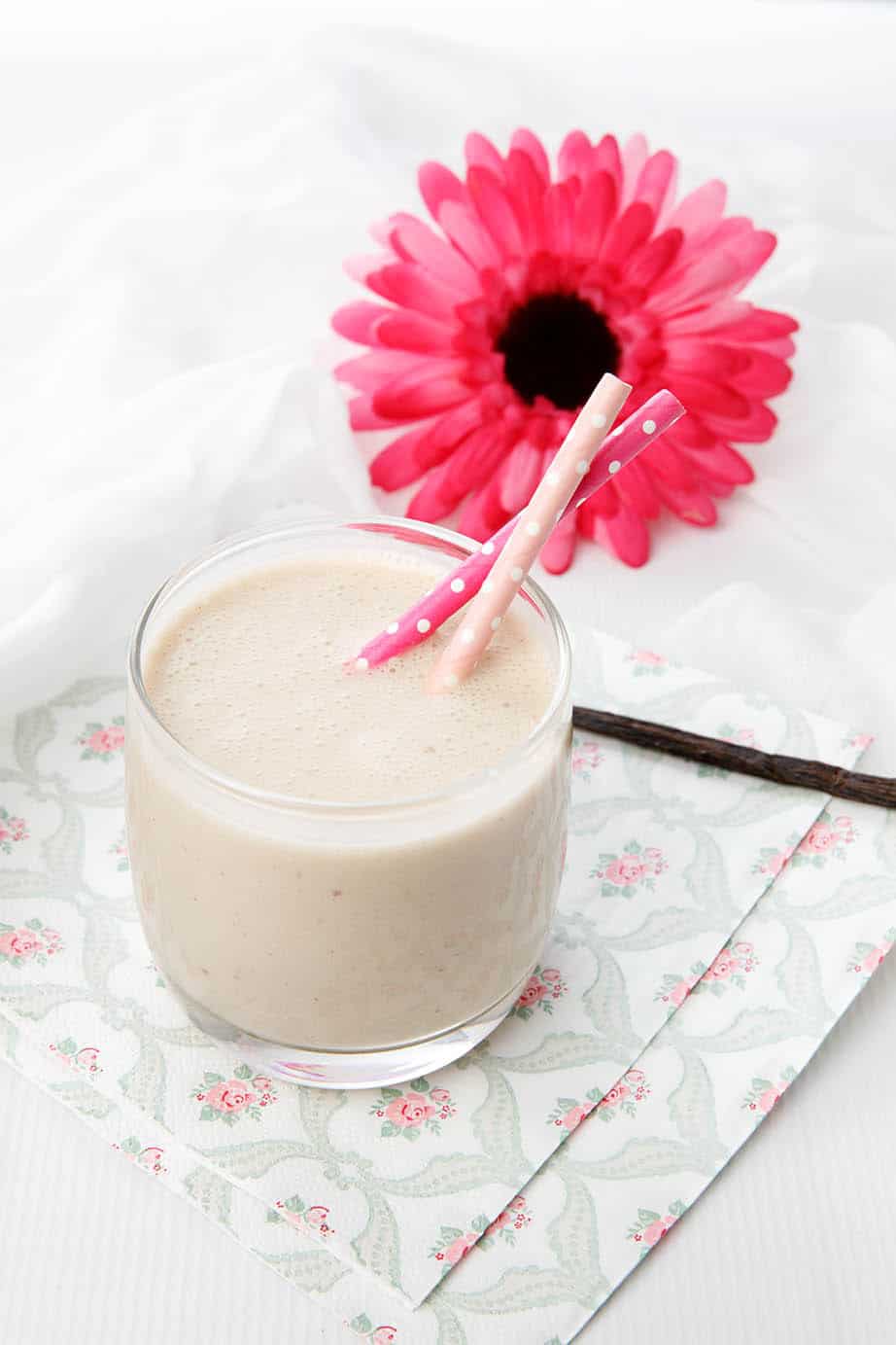 Portrait image of smoothie with a pink flower on a napkin and white background