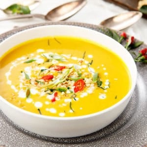 Thai Pumpkin Curry in a white bowl with herbs and chili surrounding the dish