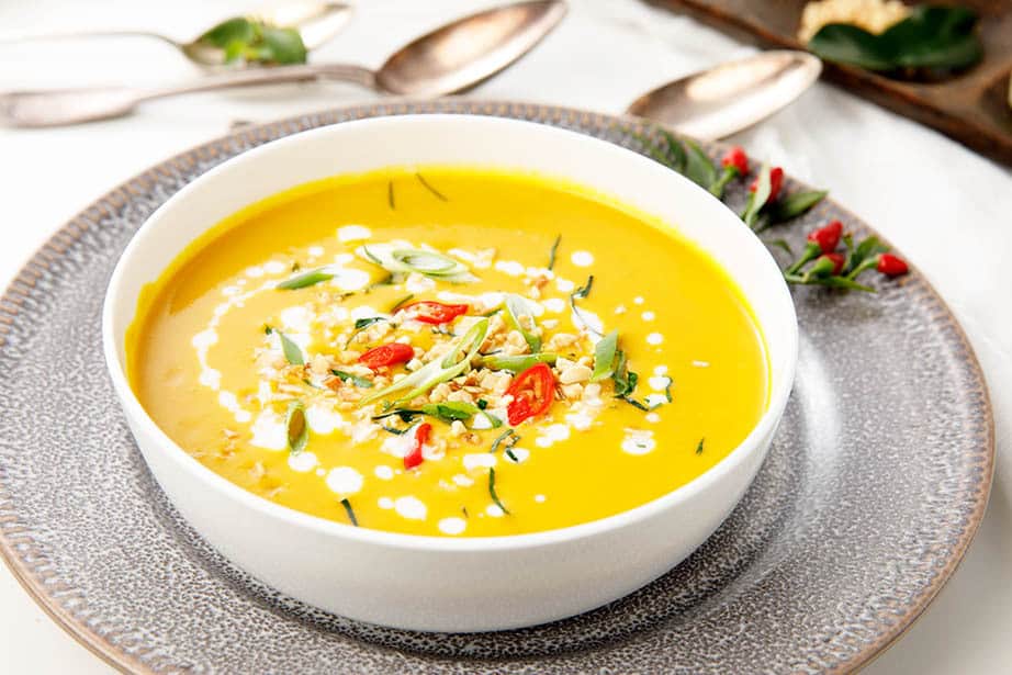 Thai Pumpkin Curry in a white bowl with herbs and chili surrounding the dish