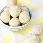 Portrait image of lemon bliss balls in a blue striped bowl on a yellow tea towel