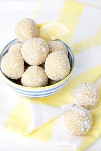 lemon bliss balls in a blue striped bowl on a yellow tea towel