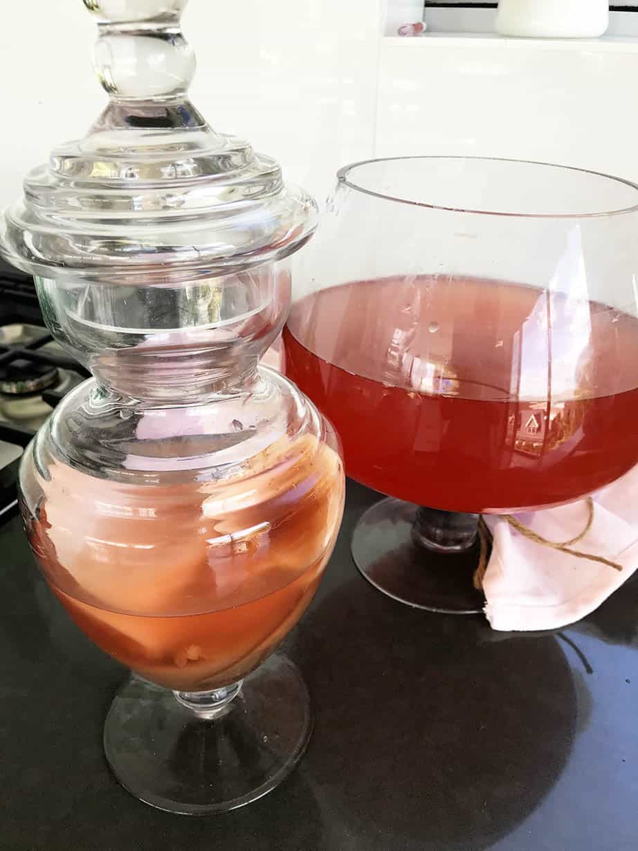 Rosehip Kombucha Tea in Glass brewing vessel on black bench