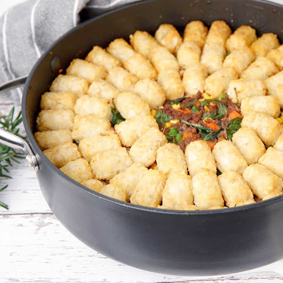 Close up square image Thermomix Shepherds Pie with potato gems in a round backing dish on white background