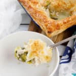 Chicken pie on a chopping board with a slice in a white bowl