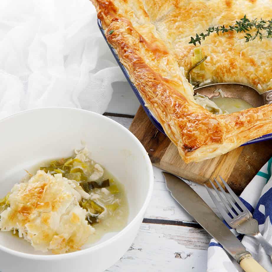 Square image chicken and leek pie on a white wood background