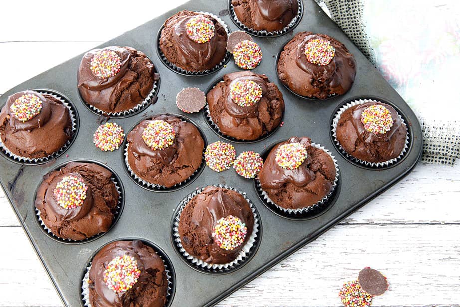 Overhead shot double chocolate muffins in a tray on a white wood background