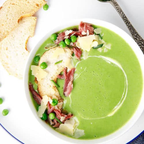 Overhead shot pea and ham soup with croutons in white bowl