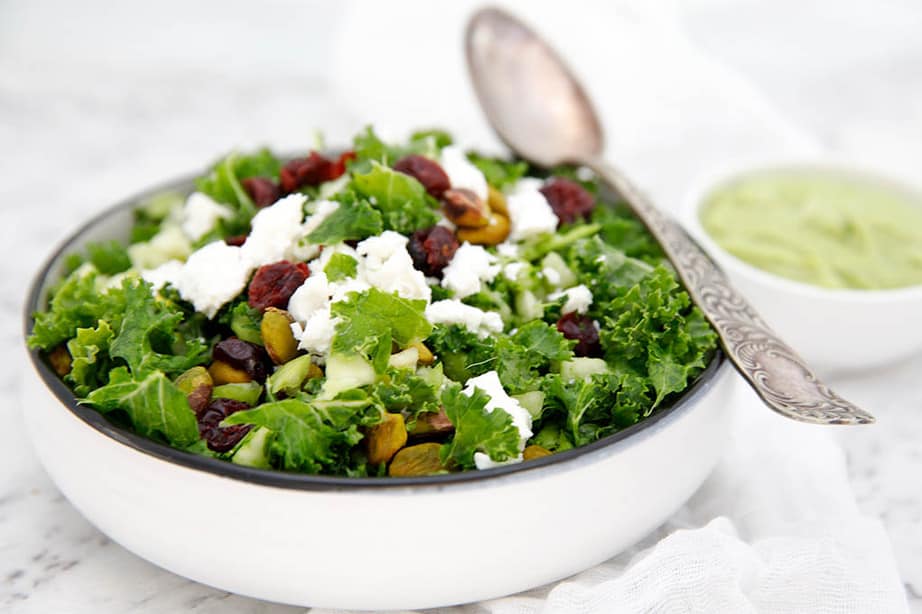  white bowl of Kale salad with cranberries on white background