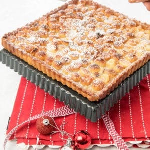 Macadamia Tart on red tea towel being dusted with icing sugar