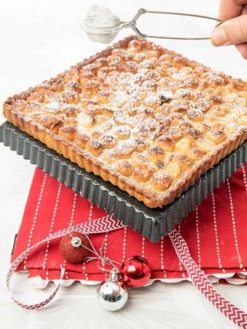 Macadamia Tart on red tea towel being dusted with icing sugar