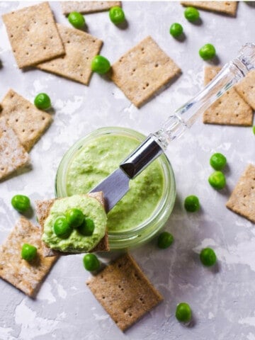 Pea bean & Feta dip on a grey background with crackers