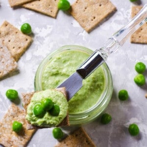 Overhead close up of smashed Bean and Pea Dip and crackers on a grey background