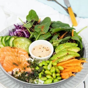 Portrait image Poke bowl on a grey plate and white background include salad items and salmon