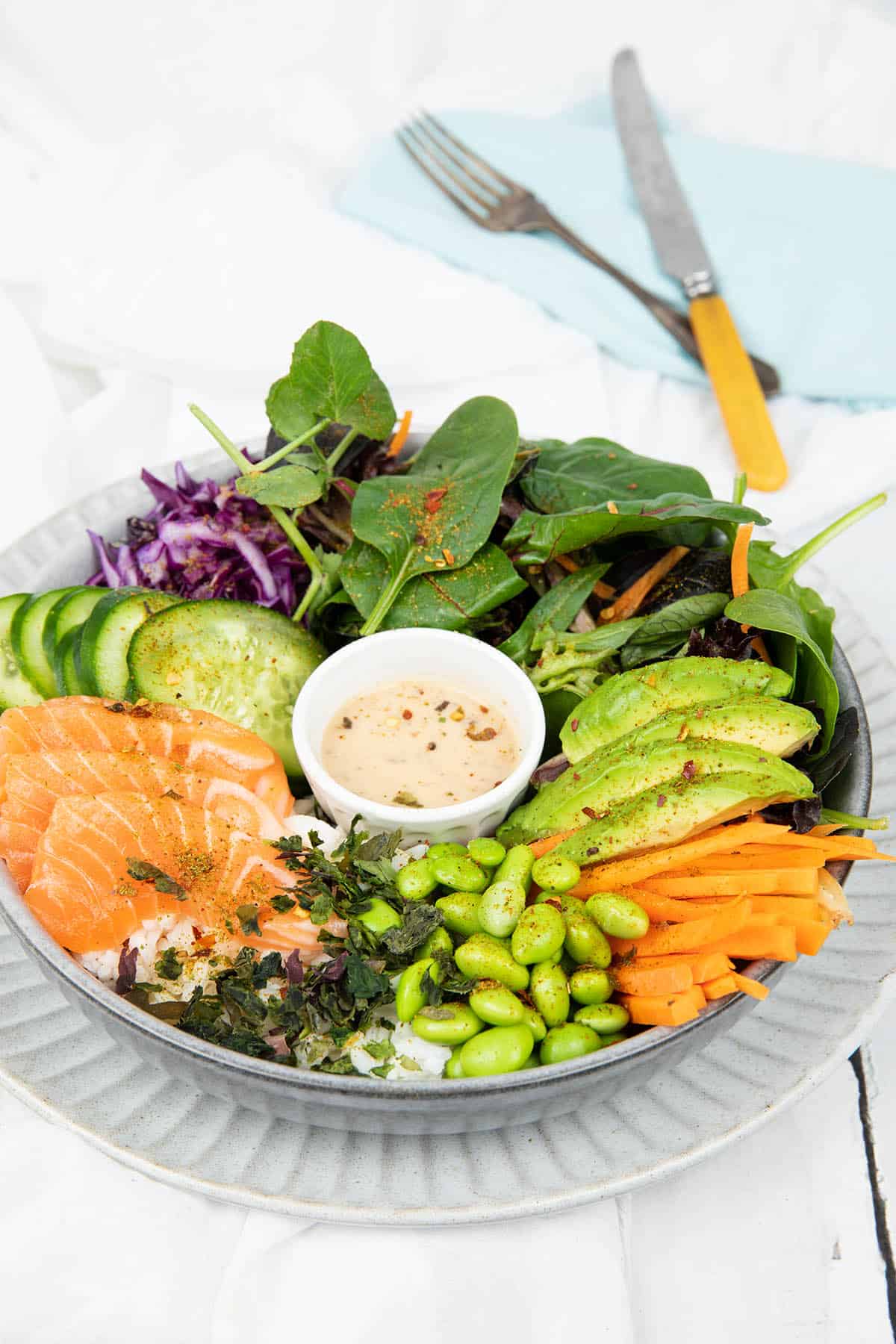 Portrait image Poke bowl on a grey plate and white background include salad items and salmon