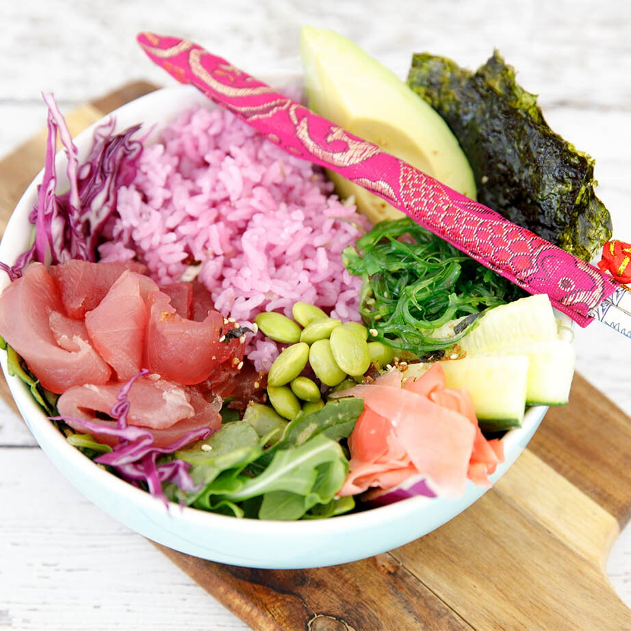 Square crop of pink rice tuna poke bowl on wooden board