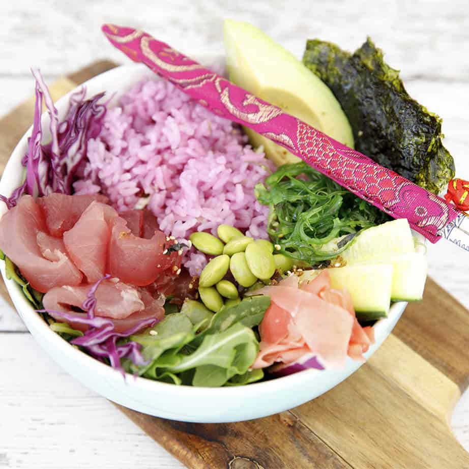 Square crop of pink rice tuna poke bowl on wooden board