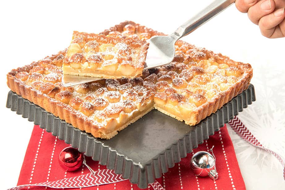 A slice of Caramel Macadamia tart being lifted from the cake tin