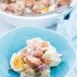 Salmon Potato salad on a blue plate with white background and blue napkin