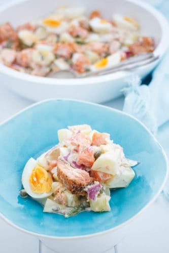 Salmon Potato salad on a blue plate with white background and blue napkin