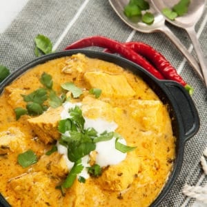 Overhead shot Easy Chicken Curry in black pan with yoghurt and chili