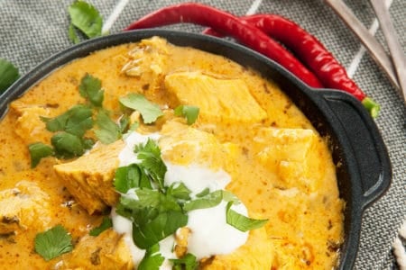 Overhead shot Easy Chicken Curry in black pan with yoghurt and chili