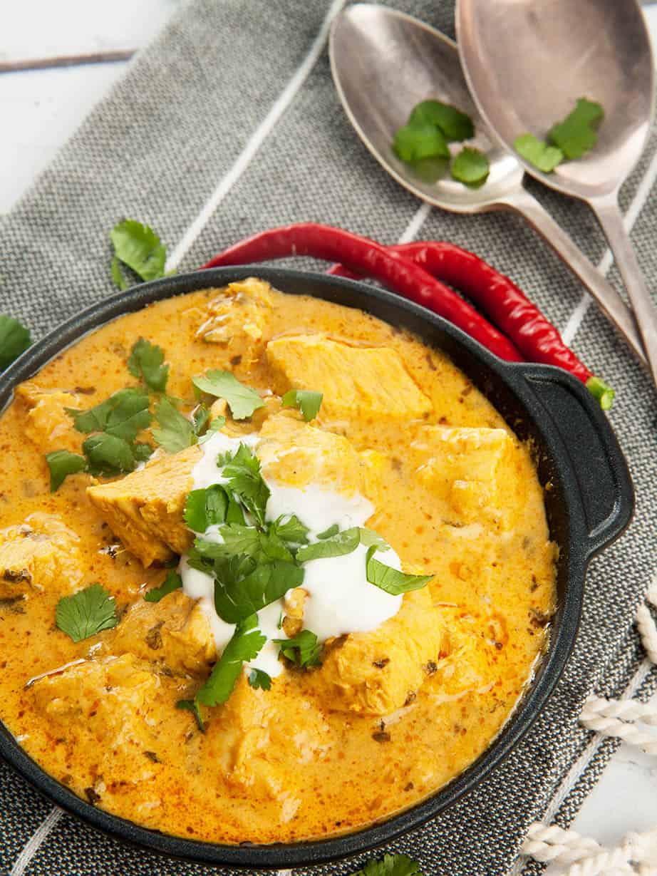 Overhead shot Easy Chicken Curry in black pan with yoghurt and chili