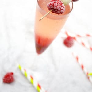 Overhead picture of a raspberry champagne cocktail on white background